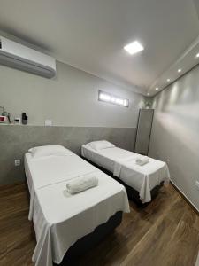 two beds in a hospital room with white sheets at Casa Lua Flat in Brumadinho