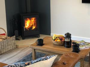 a living room with a fireplace and a table with a bowl of fruit at The Old Dairy - Uk31253 in Middleton