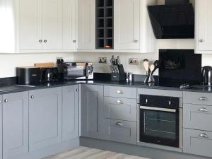a kitchen with white cabinets and a black oven at The Old Dairy - Uk31253 in Middleton