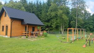 a log cabin with a playground in the yard at Noclegi u Nikoli in Wola Wereszczyńska