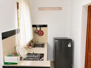a small kitchen with a refrigerator and a sink at Bendul Retreat in Tabanan