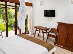 a bedroom with a bed and a desk and a tv at Bendul Retreat in Tabanan