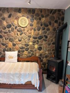 a stone wall with a bed and a wood stove at Jardin de Estrellas in San Marcos Sierras