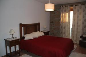 um quarto com uma cama vermelha com duas mesas e uma janela em Alojamento Rural Casa da Eira em Murça