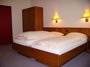 two beds in a bedroom with two lamps on the wall at Hotel an der Hauptallee in Bad Pyrmont