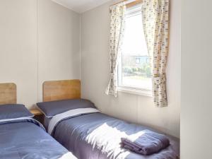 two beds in a room with a window at The Hideaway - Uk49292 in Morecambe +5 photos