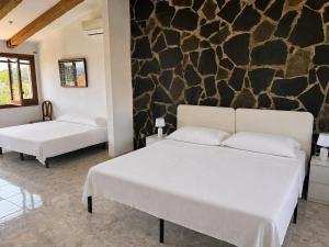 two beds in a room with a stone wall at Casa Lluna De Mar in L'Ampolla