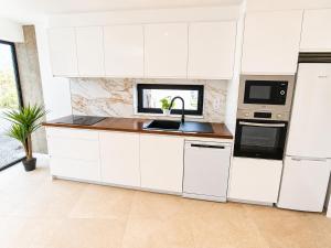 a kitchen with white cabinets and a sink at Villa Drago in Antigua