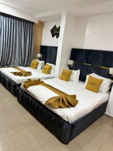two beds in a hotel room with yellow pillows at Mareot Hotel and Lounge in Maiyegun