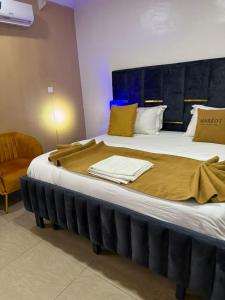 a large bed with a yellow blanket on top of it at Mareot Hotel and Lounge in Maiyegun
