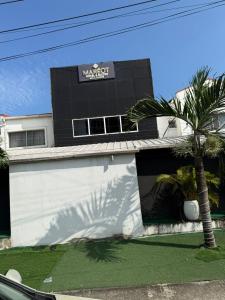 a black and white building with a palm tree in front at Mareot Hotel and Lounge in Maiyegun