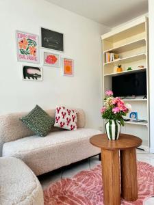 a living room with a couch and a table with flowers at Lumières de Tuffeau in Château-du-Loir