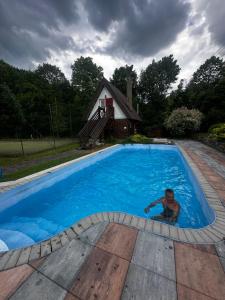 a man is sitting in a swimming pool at Goralské chalupy in Zálesie