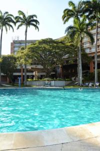 a swimming pool with palm trees in front of a building at Hotel Jirahara in Barquisimito