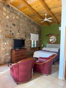 a bedroom with a bed and a tv and some chairs at Vayu- en La Casa de Nanda in San Javier