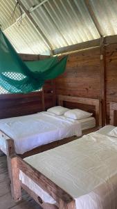 two beds in a room with a roof at Cabañas Wailidub, San Blas in Ogobsitupo