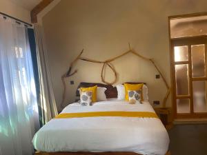 a bedroom with a large white bed with yellow pillows at Osinoni Cottages in Isiolo