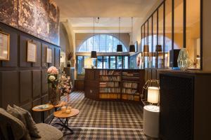 ein Zimmer mit einer Bibliothek, ausgestattet mit einer Couch und Tischen in der Unterkunft Hotel Maison Lia in Châlons-en-Champagne + 23 Fotos