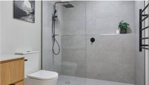 a white bathroom with a shower and a toilet at The nook in Rāmnagar