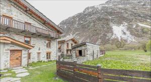 a building with a fence in front of a mountain at Chalet le Vernès Marmotte in Bonneval-sur-Arc