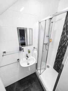 a white bathroom with a sink and a shower at Tregonholme Hotel in Bournemouth