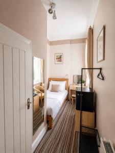 a small bedroom with a bed and a desk at Tregonholme Hotel in Bournemouth