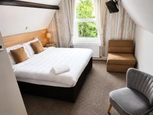 a bedroom with a bed and a chair and a window at Tregonholme Hotel in Bournemouth +11 photos