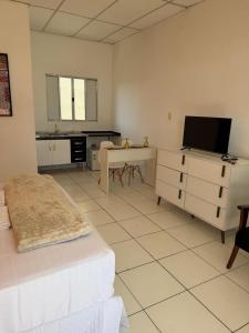 a bedroom with a bed and a desk with a television at Golden Stay Suites in Jacareí +5 photos