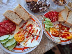two plates of food on a table with bread and vegetables at OMKA Guest House in Toktogul