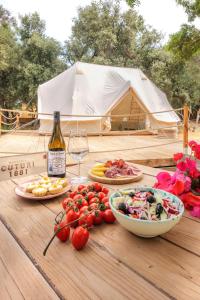 a table with plates of food and a bottle of wine at Glamping Masseria Cuturi in Manduria