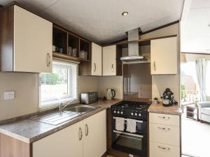 a kitchen with a sink and a stove top oven at Avon Lodge in Hyssington