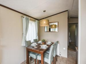 a dining room table with chairs and a chandelier at Avon Lodge in Hyssington