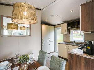 a kitchen with a table and chairs and a chandelier at Avon Lodge in Hyssington