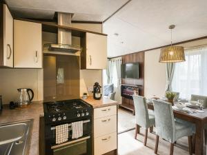 a kitchen with a stove and a table with chairs at Avon Lodge in Hyssington