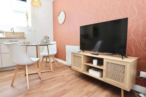 a living room with a flat screen tv on a wooden stand at Le Corail - centre-ville - TV in Pontivy