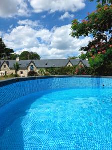 a large blue swimming pool in front of a house at Ty Kerouannec in Guilligomarcʼh