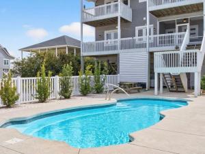 a villa with a swimming pool in front of a house at Mischief Managed NC in Oak Island