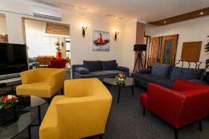 ein Wohnzimmer mit Sofas, Sesseln und einem Fernseher in der Unterkunft Hotel Mediterran Budapest in Budapest