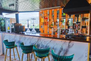 a bar with four green bar stools at Hotel Boutique Adam in Tbilisi City