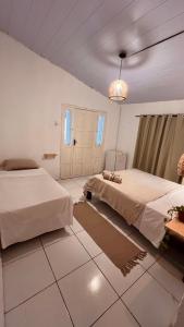 a bedroom with two beds and a chandelier at Casa Folha Tropical in Pipa