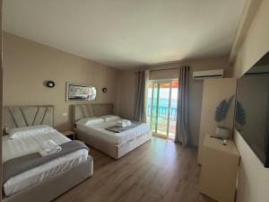 a hotel room with two beds and a television at Yamas Hotel "Ex Malibu" in Dhërmi