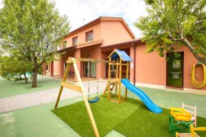 a playground in front of a pink house at Cuencaloft Villa Los Perales in Villalba de la Sierra