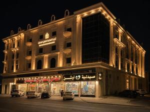 a lit up building with cars parked in front of it at اجنحة الفخامة للشقق الفندقية in Taif