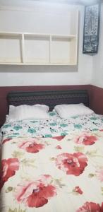 a bed with a floral comforter and two pillows at IVATO Airport STUDIOS CHAMBRES in Ivato