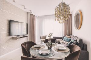a living room with a table and chairs and a chandelier at Maritimo Apartament przy Porcie by 2HomeRent in Kołobrzeg