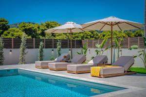 a pool with chairs and umbrellas next to a swimming pool at Alpha Waves By Banana Beach in Vasilikos