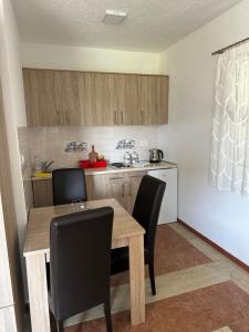 a kitchen with a wooden table and black chairs at Apartmani Čavor in Budva