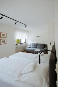 a white bedroom with two beds and a couch at Hotel Am Waldschwimmbad in Bürstadt