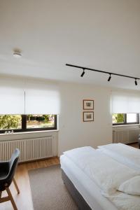 a bedroom with a bed and a chair and windows at Hotel Am Waldschwimmbad in Bürstadt