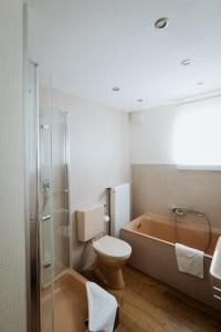 a bathroom with a tub and a toilet and a sink at Hotel Am Waldschwimmbad in Bürstadt